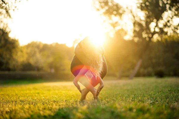 Yoga in het park, buiten met effect lichte zonsondergang, gezondheid vrouw. Vrouw met sport lichaam — Stockfoto