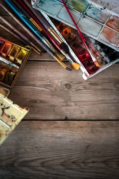 Background with used paint brushes and watercolor paints on old wooden boards. Place for text. Top view with copy space — Stock Photo, Image