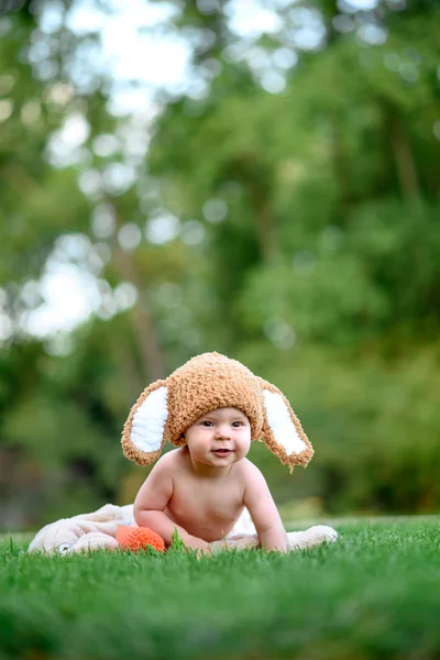 Dziecko w kapeluszu jak królik z marchewką zabawki na zielonej trawie na zewnątrz — Zdjęcie stockowe