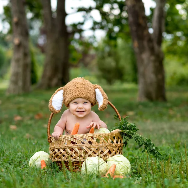 Dziecko w kapeluszu jak królik z marchewką zabawki na zielonej trawie na zewnątrz — Zdjęcie stockowe
