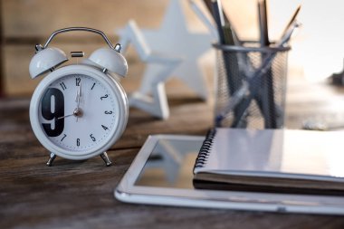 Modern kavramsal ahşap ofis veya ev büro masa tablet, not defteri, fincan kalemler ve masa saati.