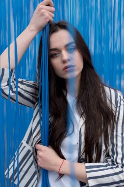 Modaya uygun olarak mavi arka plan üzerinde poz montlu genç güzel kadın. Yağmur kavramı