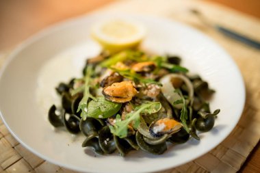 Siyah makarna deniz ürünleri beyaz krema sos ve limon ile