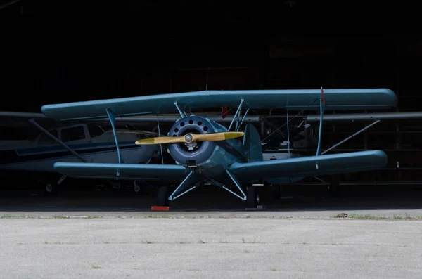 Ljusblå Bi-plan vid öppningen till en hangar. — Stockfoto