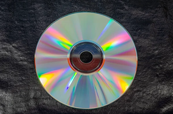 Overhead view of a single CD on black leather — Stock Photo, Image