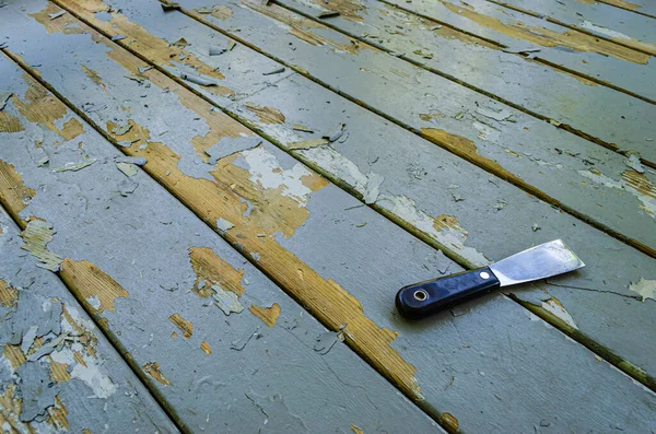 Angled view of a putty knife laying on gray wooden boards next t — 스톡 사진