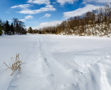 Donmuş kar birikintisi kar motosikleti izleriyle kaplı.