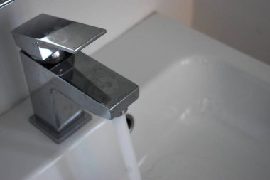 Akan suyu olan bir banyo musluğunun yakın çekimi. El yıkama ve hijyen kavramı