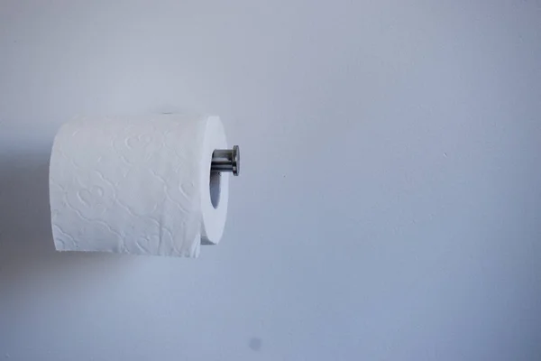 白い壁に対してホルダー上のトイレットペーパー トイレタリーペーパーパニック購入 ホーディングコンセプト — ストック写真