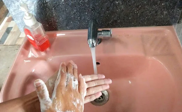 Hand washing with liquid hand wash in basin tap, soapy hand ,precaution for corona virus infection