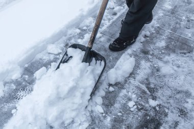 Adam bahçedeki karları temizler.