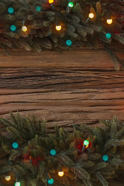 Ramo de árvore de Natal e luzes no fundo de madeira. Vista com espaço de cópia — Fotografia de Stock