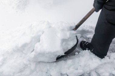 Bir kürekle bir sürü kar temizliyorum.