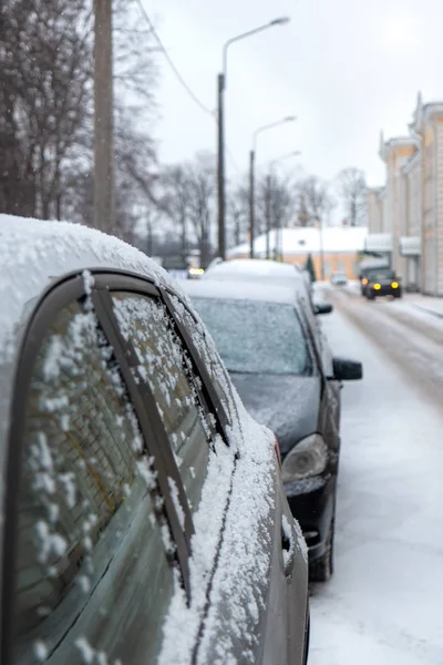 parked cars on the side of the road dusted with snow