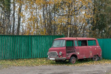 Eski terk edilmiş araba çitin yanında duruyor.