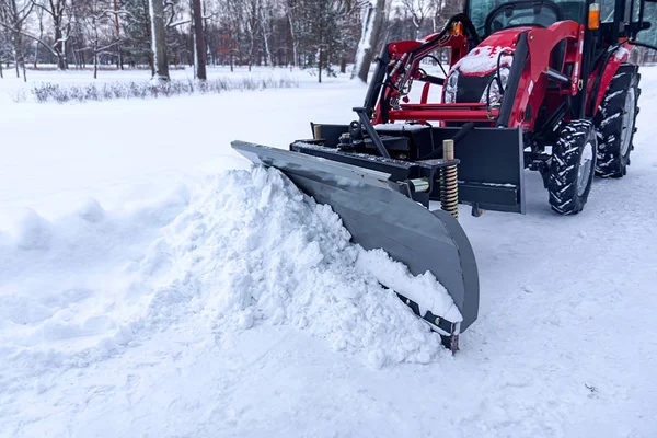 红色拖拉机用桶从公园的路上除雪 — 图库照片