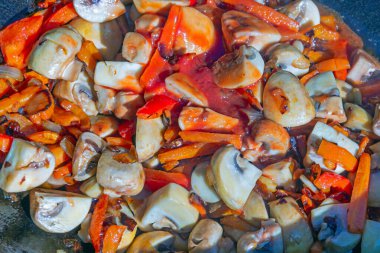 Kırmızı biber, havuç ve soğan ile dilimlenmiş şampiyon mantarları yakın plan bir tencerede. Sağlıklı ve sağlıklı vejetaryen yemekleri pişirmek. Evde pişir..