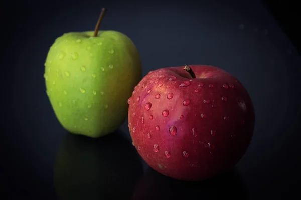 Two fresh green and red apple on a dark black background