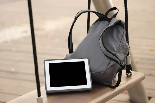 Tablet ve sırt çantası parkta bir bankta.