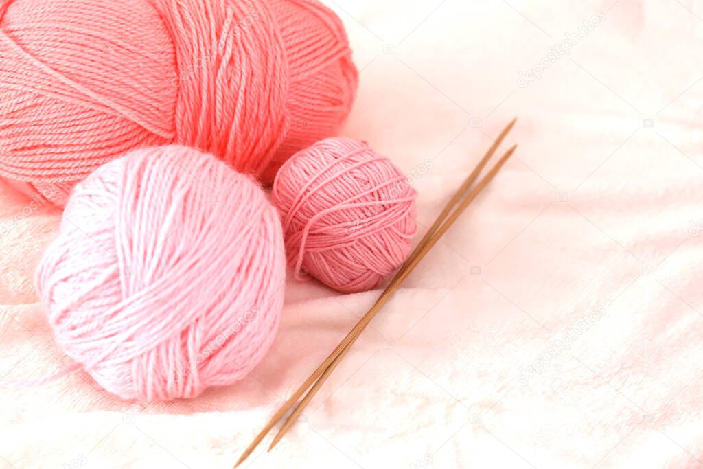  pink balls of yarn and knitting needles