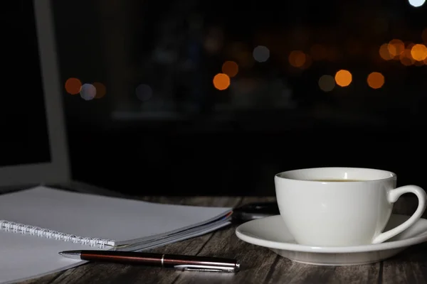 work from home, a cup of coffee and a laptop on a night background with beautiful bokeh