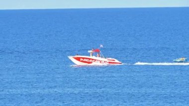 Mutlu turistler mavi denizde şişme bot sürerken eğleniyorlar.