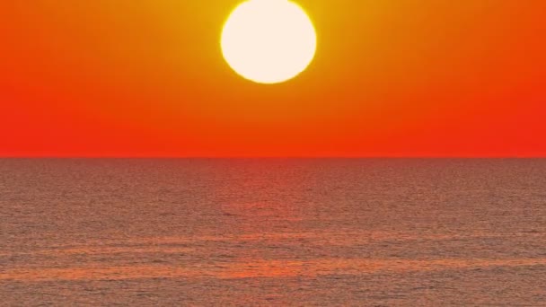 Sol grande abajo sobre mar, cielo rojo cámara lenta 4k — Vídeo de stock