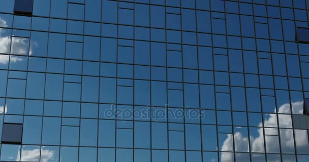 AERIAL. Movimento suave da câmera na frente das janelas do prédio de escritórios refletindo o céu azul ensolarado com nuvens inchadas brancas. 4k — Vídeo de Stock
