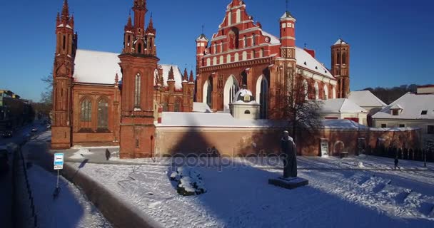 AERIAL. Voo suave através das torres da Igreja de Santa Ana (Onos) cobertas de neve, Vilnius, Lituânia. Dia de inverno ensolarado. 4k — Vídeo de Stock