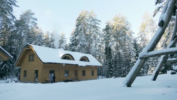 En el momento oportuno. Mañana fría y soleada de invierno en Lituania, Gudasiai (madera de Gredaiciai). Casa con chimenea humeante. 4k — Vídeo de stock