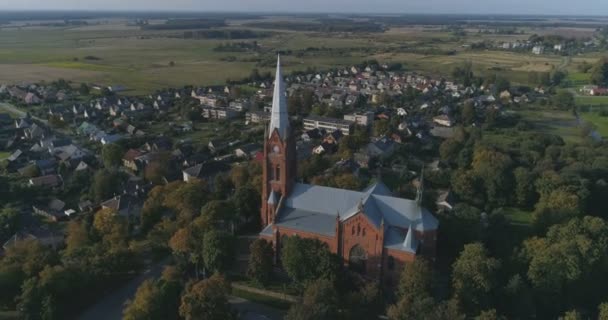 Luchtfoto. Vloeiend punt van belang drone shot van St. John kerk van Ramygala in Litouwen. Panorama van de stad in het vroege najaar. 4k — Stockvideo