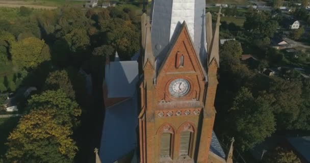 AERIAL. (Primer plano) Punto suave de interés plano de dron de la iglesia de San Juan de Ramygala en Lituania. Panorama de la ciudad a principios de otoño. 4k — Vídeo de stock