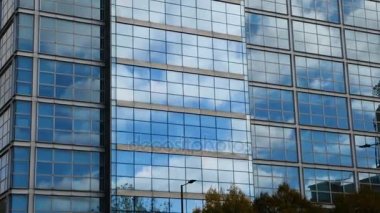 Hava. Pürüzsüz kamera hareketi ofis windows güneşli mavi gökyüzü beyaz bulutlar ile yansıtan binası önünde. 4k