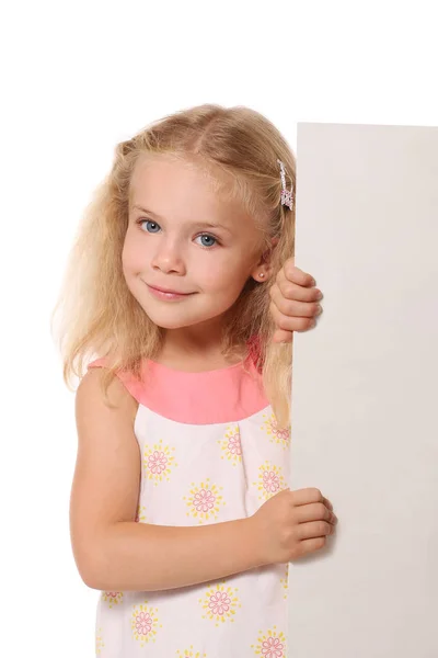 Маленькая девочка выглядывает из-за белой простыни на белом спинке — стоковое фото