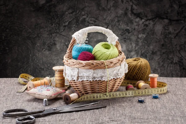 Bundles of thread in the basket, scissors and thread in drums on — Stock Photo, Image