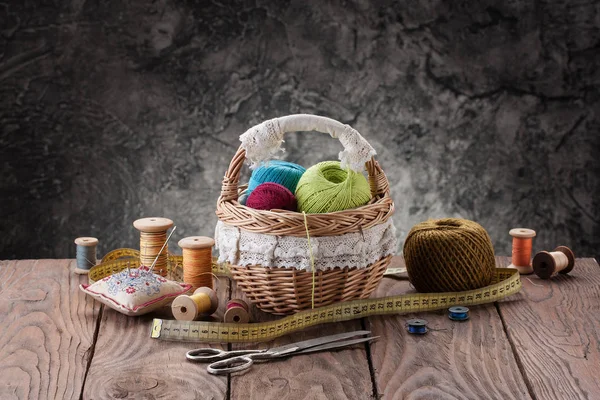 Bundles of thread in the basket, scissors and thread in drums on — Stock Photo, Image