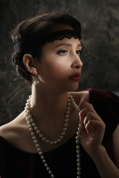 Belle fille brune avec des perles dans un style rétro Image En Vente