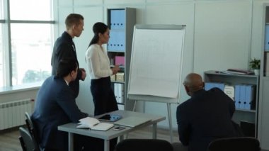 Ben başka bir Suggestion/In büyük pencereler ekibi ile geniş ofis var mali rapor anlatılmaktadır. Tablet, dizüstü bilgisayar ve kalem masanın üzerinde. Onlar iş takım elbiseli giyindin. Onlara, büyük pencereler, dolaplar klasörlerle, bir flipchart