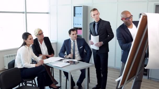 J'ai une solution intéressante ! / Dans le bureau spacieux avec de grandes fenêtres équipe discute du rapport financier. La tablette, l'ordinateur portable et les stylos sur la table. Ils sont habillés en costume d'affaires. Derrière eux, de grandes fenêtres, des armoires avec des dossiers, un pallier 