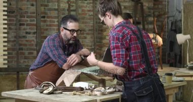 Ahşap mobilya restorasyon Atölyesi / An bir aile ağaç işleme dükkanında ortalama gün. Genç adam cilalar cabrioli bacak önce kaplama bitirme