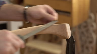 Marangoz cilalar Cabrioli bacak onun atölye/kabine Maker cabriolet bacak bir dosyayla parlatıyor. O küçük aile Doğramacılar dükkanında çalışıyor