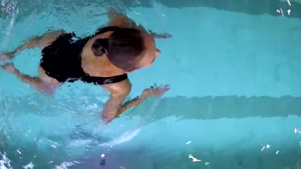 Молода жінка плаває в басейні — стокове відео