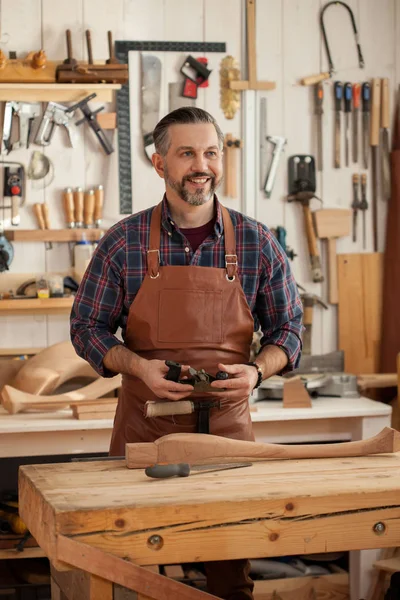 Happy Carpenter. Middle ages handsome carpenter finished creating cabriolet legs and smiles to the camera