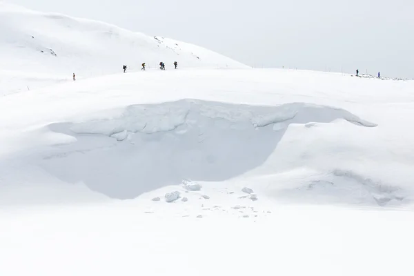 Skidåkare gå på snö täckta bergskedjor Stockfoto