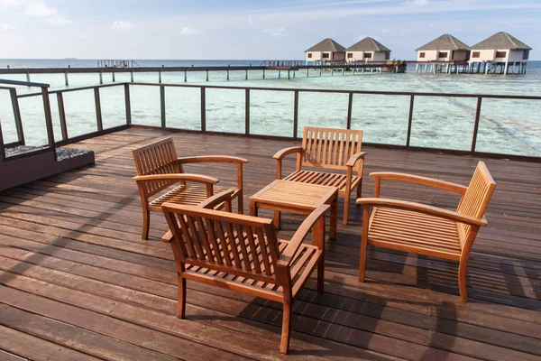 Wooden chairs at balcony with water villas background — Stock Photo, Image