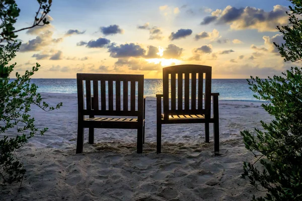 Par strandstol står inför havet under solnedgång — Stockfoto