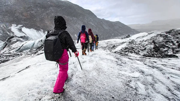 Grupo de caminhantes caminham no glaciar durante a neve em Solheimajokull , — Fotografia de Stock