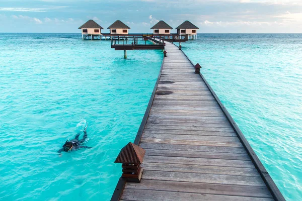 Woman snorkeling over crystal clear water at water villa — Stock Photo, Image