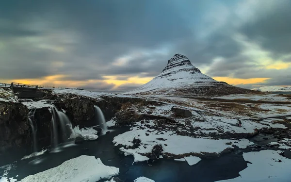 Lange Belichtung des Berges mit Wasserfall im Vordergrund im Winter Stockbild