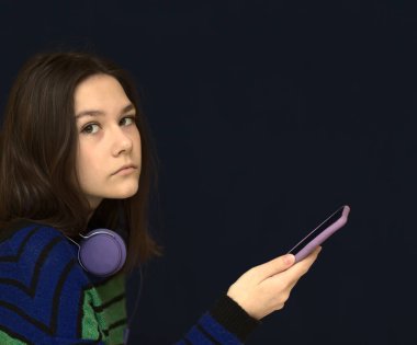 Mesaj yazan ya da akıllı telefon kullanarak sosyal ağlara kayan mutlu bir kız. Koyu arkaplan